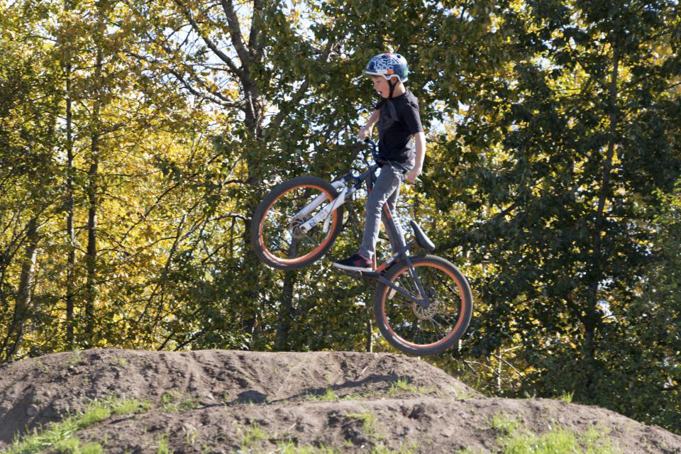 a child on a bike jumping over a mound of dirt